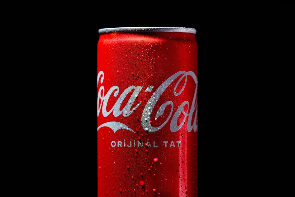 Refreshing close-up of a chilled soda can with condensation and water droplets on a black background.